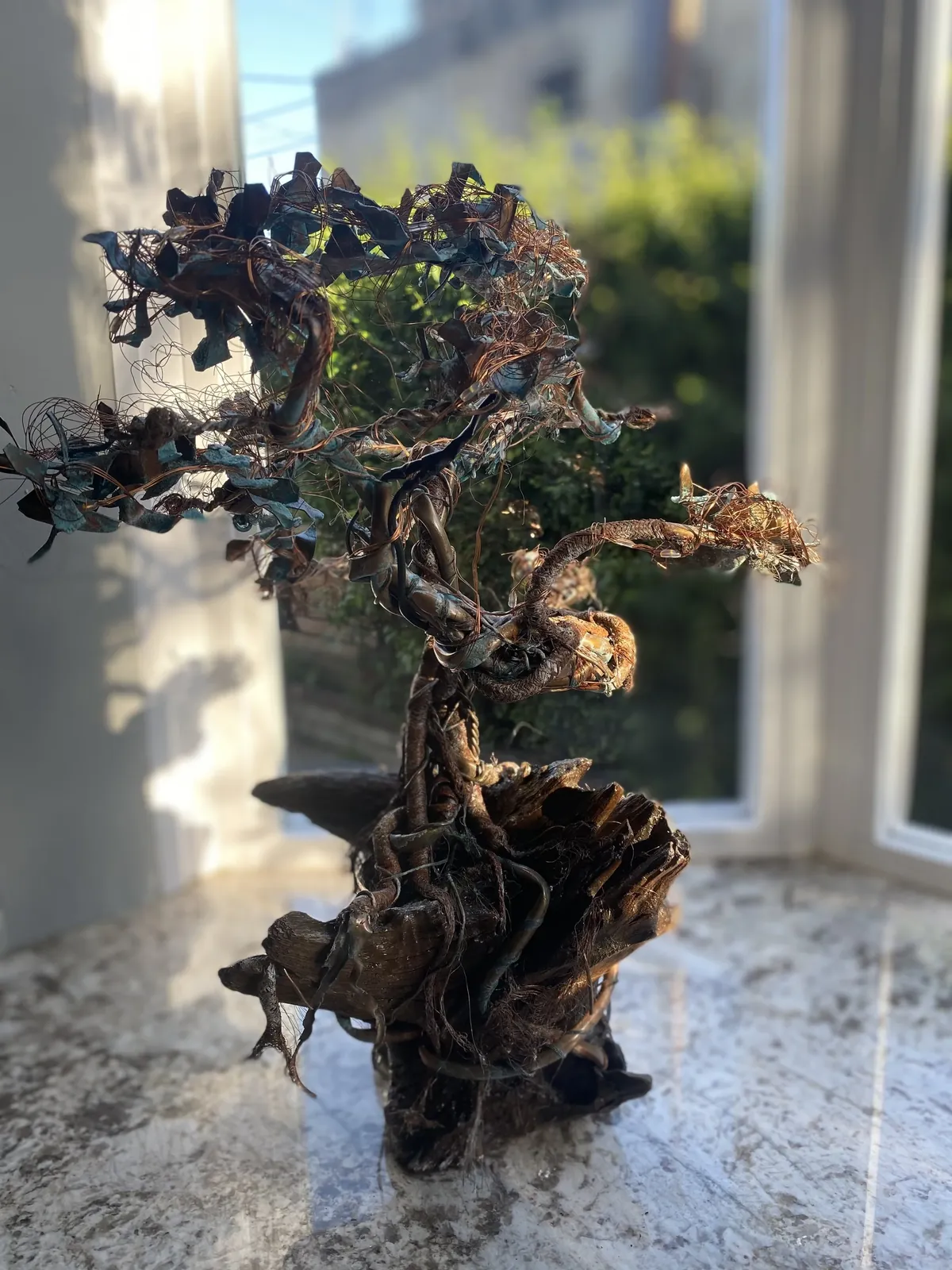 Copper and wire tree sculpture on a stone sill