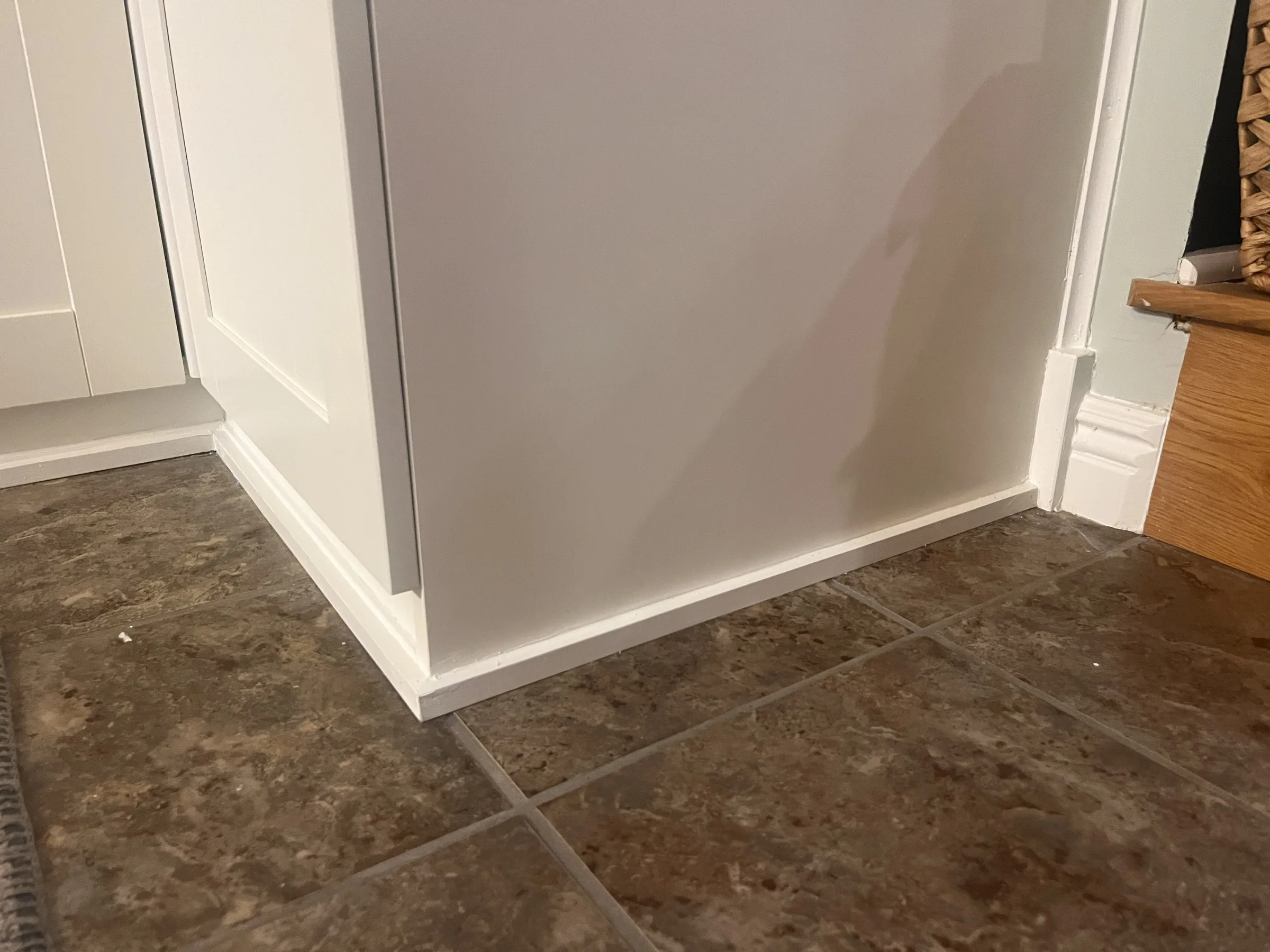 Detail of the cabinet base and toe kick meeting the tile floor at the outside corner