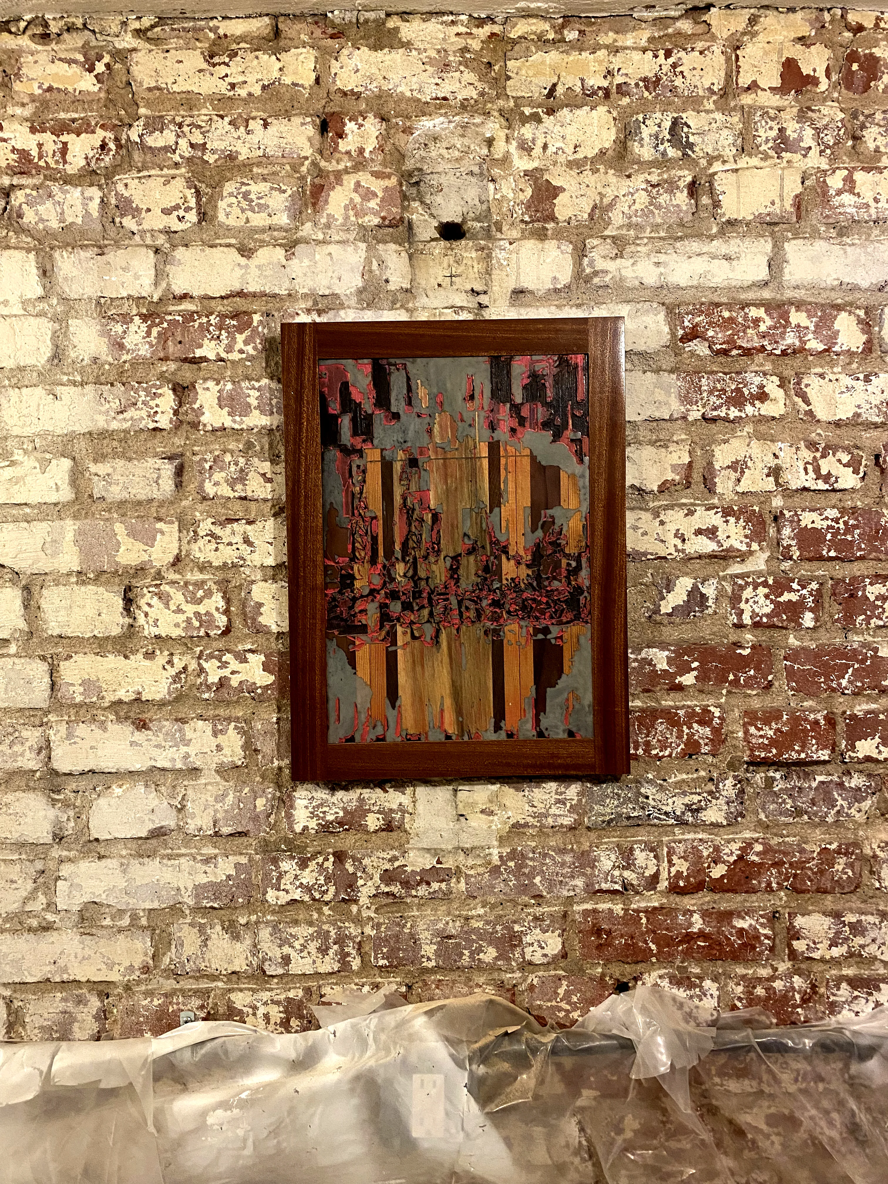 Framed resin and mixed-media inlay panel on a brick wall