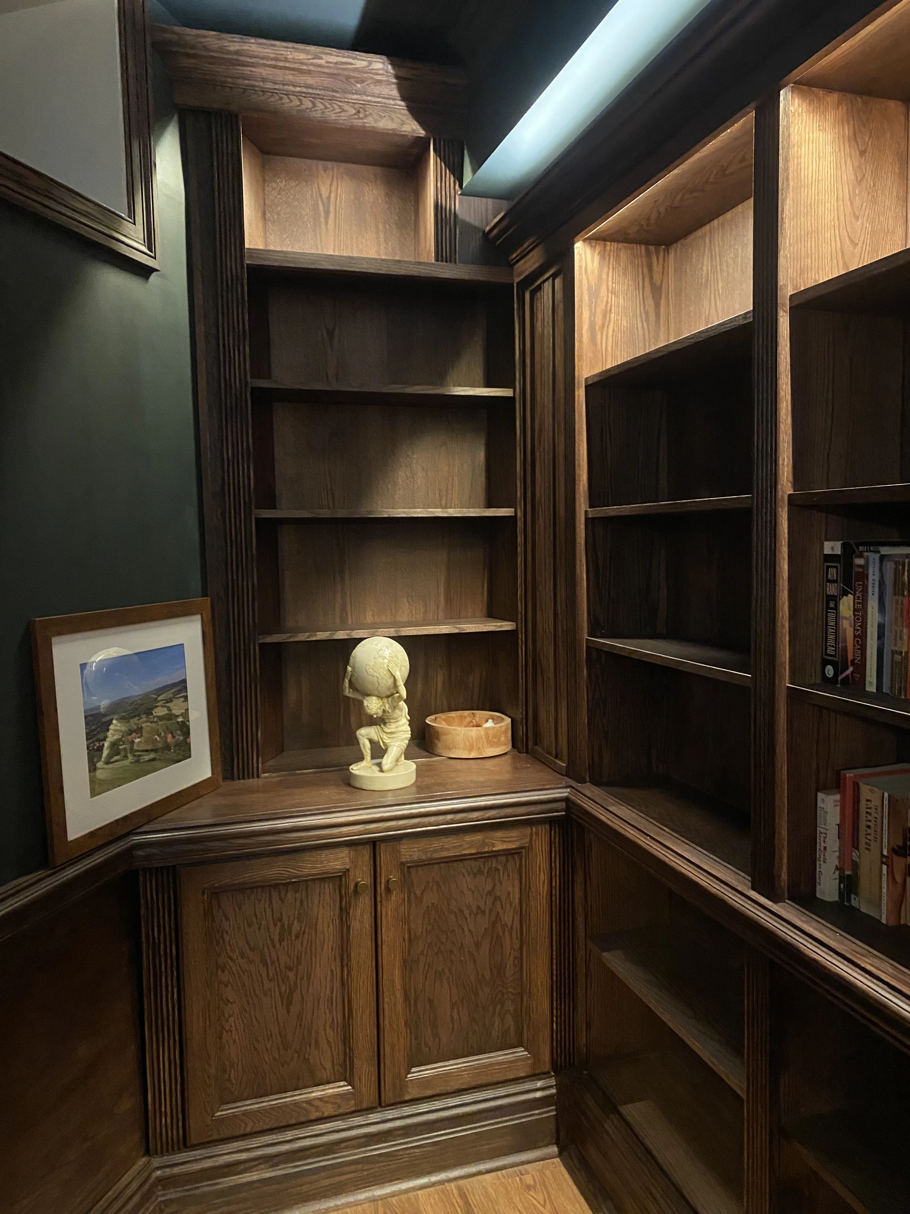 Finished custom stained-oak built-in library/study: floor-to-ceiling bookcases, base cabinets, reeded stiles, LED cove lighting