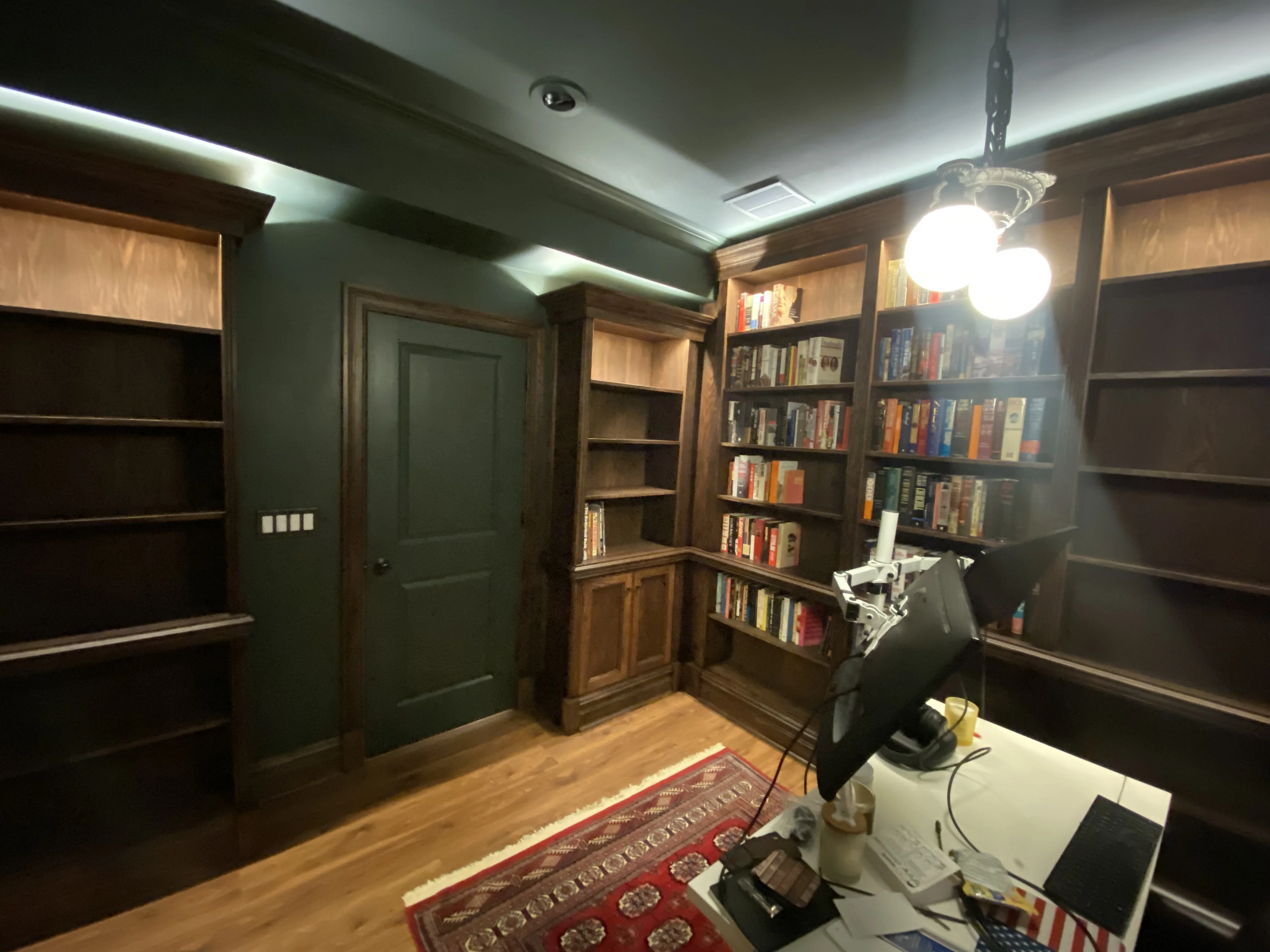 Finished custom stained-oak built-in library/study: floor-to-ceiling bookcases, base cabinets, reeded stiles, LED cove lighting