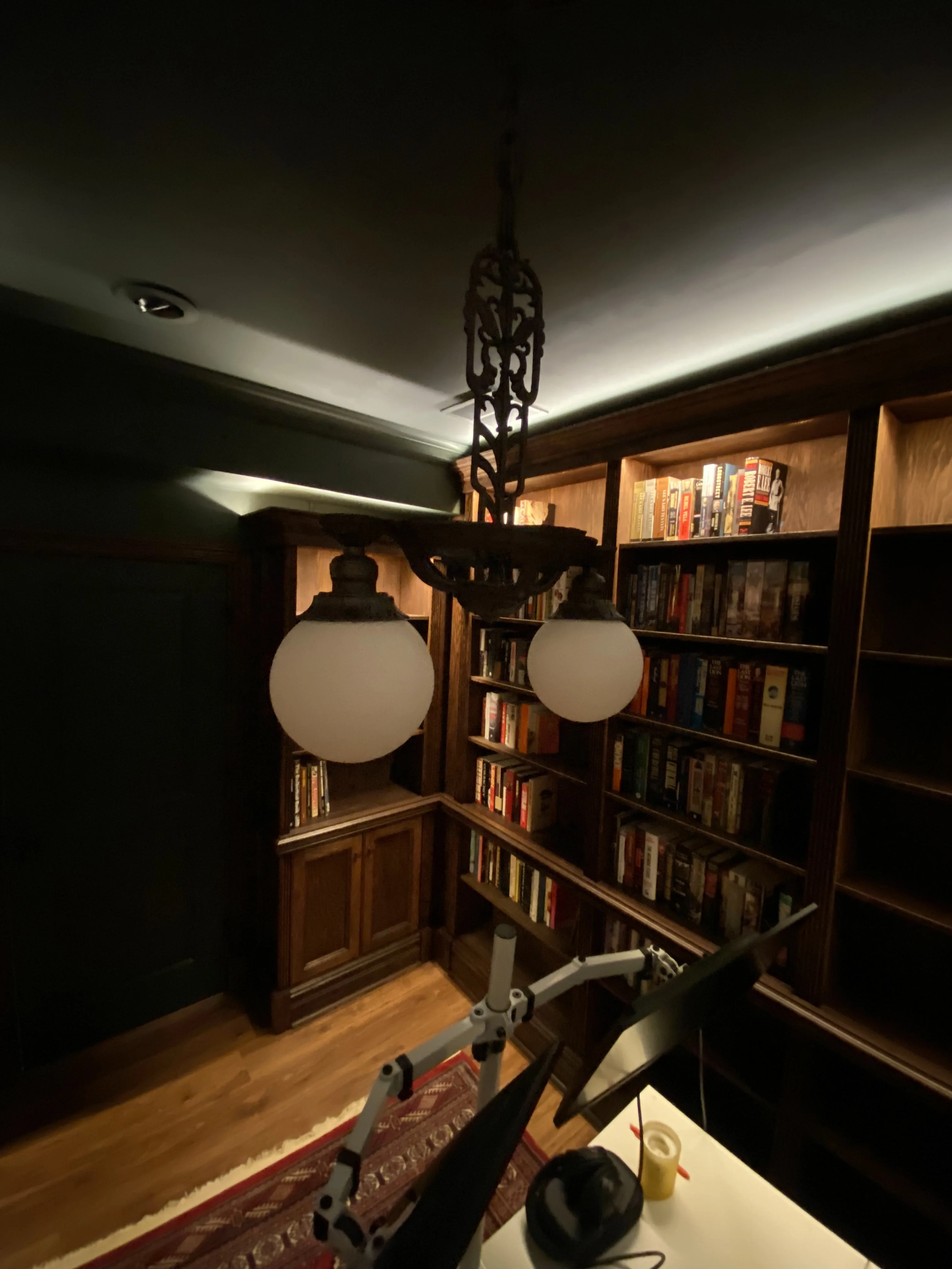 Finished custom stained-oak built-in library/study: floor-to-ceiling bookcases, base cabinets, reeded stiles, LED cove lighting