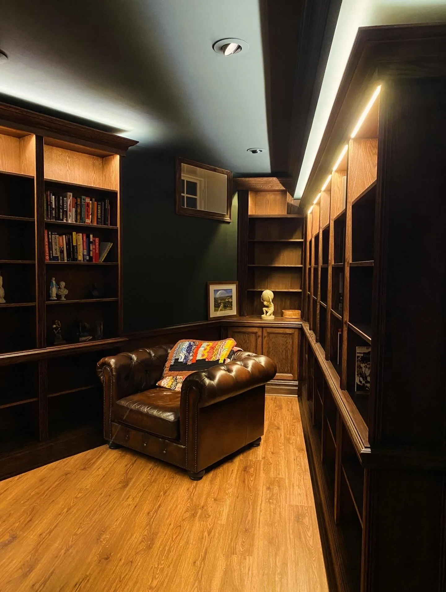 Finished dark-green study with custom built-in bookshelves, wainscoting, leather chair